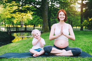 Fototapeta premium Pregnant woman, mother with son in the lotus position.