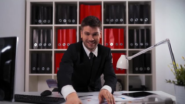 4k UltraHD. Young attractive businessman wearing a suit sitting in armchair throwing euro bills in air. modern office. teal and orange.