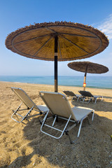 Beautiful Ionian sandy beach in Greece with with sunbeds and straw sunshades, umbrellas. Vacation destination