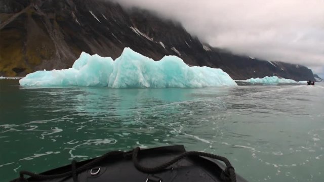 Boat sail on background Moving Ice Floes of Arctic Ocean in Svalbard. Wildlife in Nordic badlands. Unique footage on background natural landscape and snow of Spitsbergen.