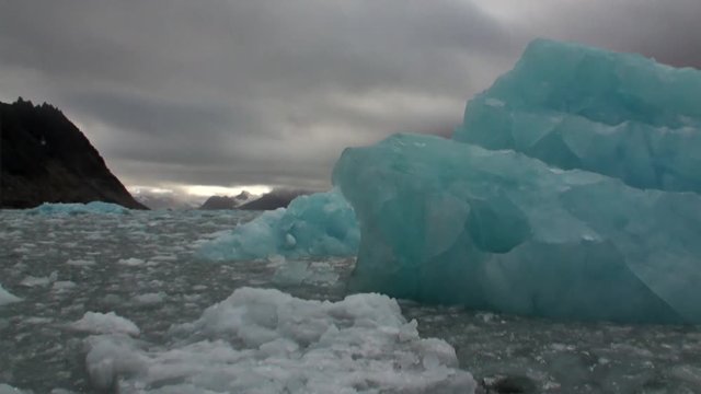 Iceberg in the water of Arctic Ocean on background of mountain in Svalbard. Wildlife in Nordic badlands. Unique footage on background natural landscape and snow of Spitsbergen.