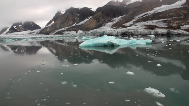 Moving Ice Floes on background of mountain on water of Arctic Ocean in Svalbard. Wildlife in Nordic badlands. Unique footage on background natural landscape and snow of Spitsbergen.