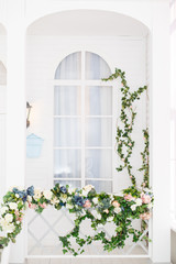 Elegant white window in spring arbor, overgrown with greenery. Rustic style. Wooden house with greenery
