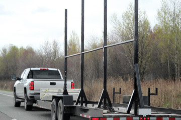 White truck pulling a trailer with metal supports for signs
