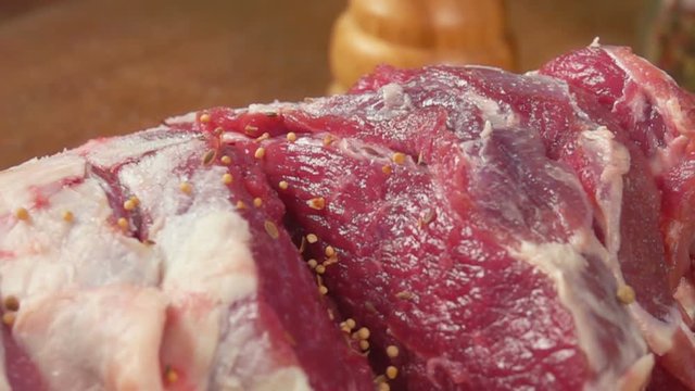 Closeup of spices falls on the leg of lamb in slow motion