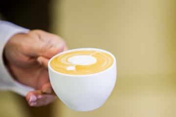 Barista serving a cup of cappuccino close up.