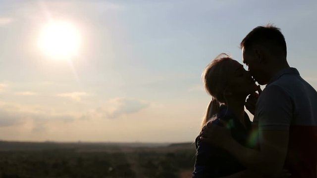 Silhouette kissing loving couple outdoors in the mountains against the sky.
