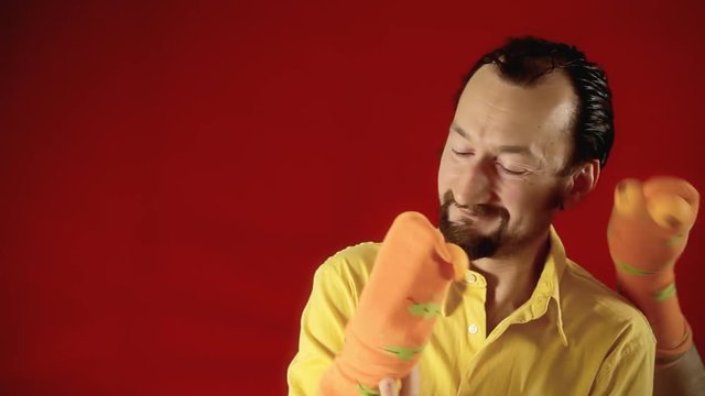 A man playing with two handmade sock puppets bickering and fighting. Room for copyspace on the left.
