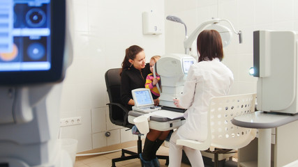Doctor optometrist examines the sight of a small child