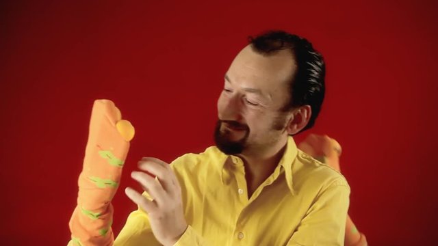 A grownup man playing with two handmade sock puppets and having fun.
