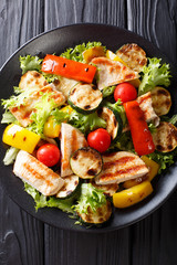 Delicious salad of grilled summer vegetables and chicken close-up on a plate. Vertical top view