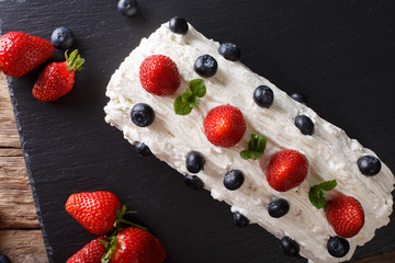 Christmas strawberry roll with whipped cream, mint and blueberries close-up on the table. horizontal top view