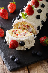 Delicious sliced strawberry cake with whipped cream, mint and blueberries close-up. vertical