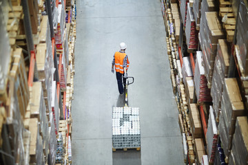 Loader pulling forklift while moving along aisle between shelves with boxes © pressmaster