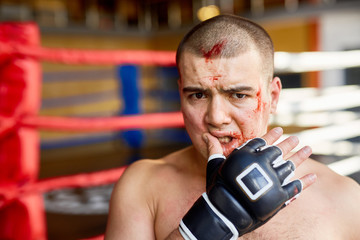 Defeated fighter with blood on face looking at camera