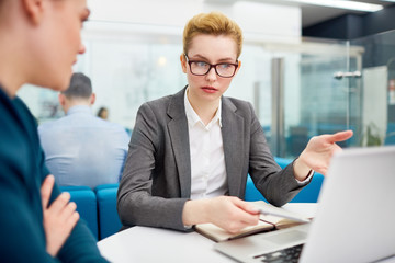 Businesswoman explaining her colleague online data in laptop