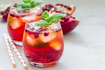 Mojito cocktail with pomegranate, mint, lemon juice and ice in glass, horizontal, copy space