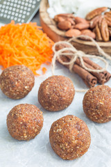Healthy paleo energy balls with carrot, nuts, dates and coconut flakes, on parchment, vertical
