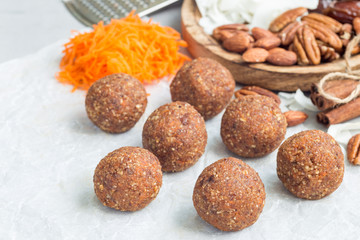 Healthy homemade paleo energy balls with carrot, nuts, dates and coconut flakes, on parchment, horizontal, copy space