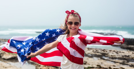 American flag. Little smiling  patriotic girl with long blond hair holding American flag on Independence day USA, July 4th. Memorial day - obrazy, fototapety, plakaty