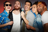Group of buddies singing karaoke in club