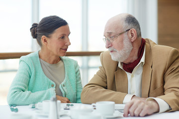 Fototapeta premium Senior couple talking by served table in cafe