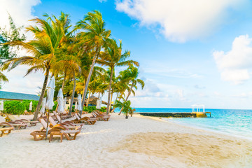 Beach chairs with umbrella at Maldives island, white sandy beach and sea .