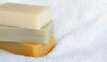 Natural homemade soaps on white bath towel background.