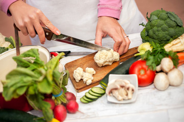 Woman cutting cauliflower with a knife