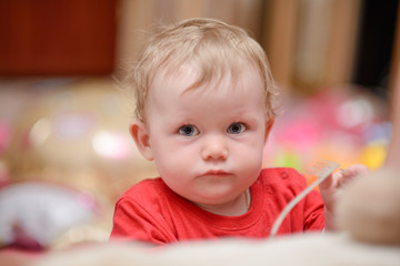 Fototapeta premium A baby boy is playing and looking at the camera