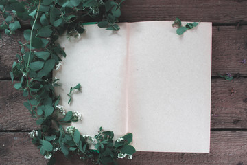 Open book with branches and flowers background.
