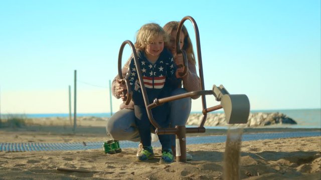 Mom and son playing with an excavator on the sandy beach