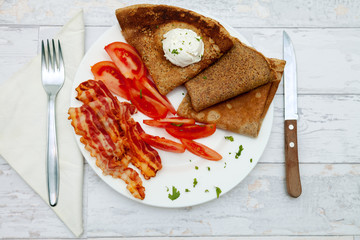 Top view on breakfast with bacon, pancakes and tomato