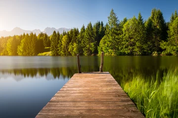Photo sur Plexiglas Jetée Idyllic view of the wooden pier in the lake with mountain scenery background. Alps in the early morning.