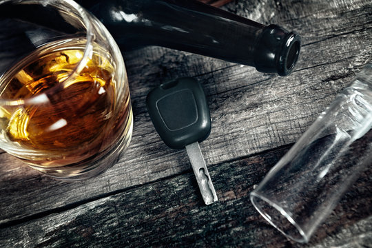Car keys on the table with alcohol drink, fallen flask and fallen glass, drive under alcohol influence concept