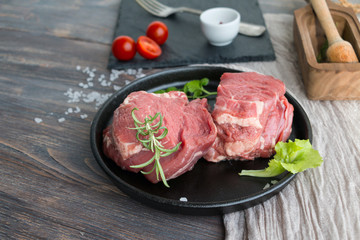 Beef sirloin - two steaks - on cast iron pan. Wooden table.