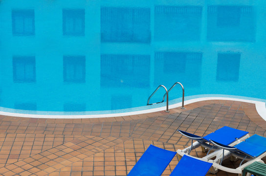 Outdoor swimming pool with stair and blue sunbad at hotel. Relax and vacation concept.Space for text.