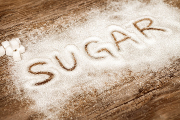 Word sugar and sugar cubes on wooden background, high sugar level and diabetes concept