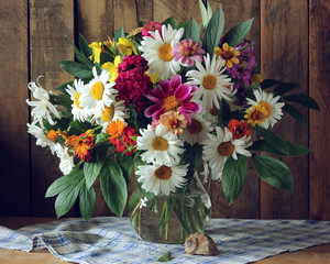 Bouquet of garden flowers in a glass jug and a shell. © Masquerade