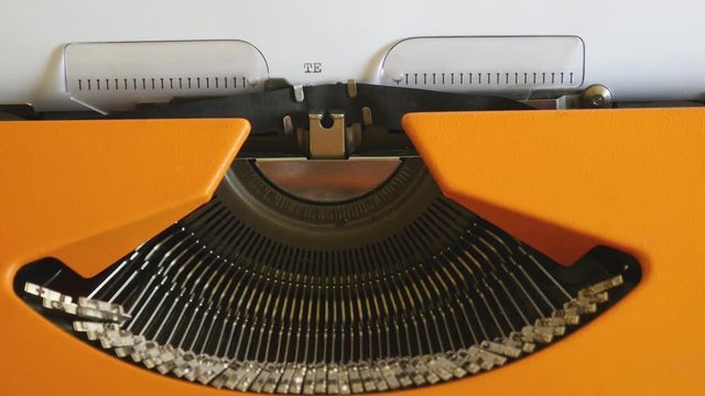 High angle footage of a person writing TERRORISM on an old typewriter, with sound