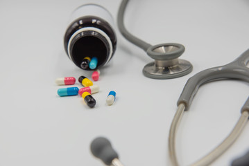 Capsules drug tablets and bottles and stethoscope on white background .