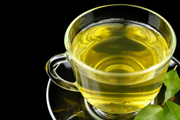 Cup of tea with green leaves on dark background