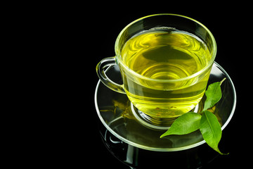 Cup of tea with green leaves on dark background