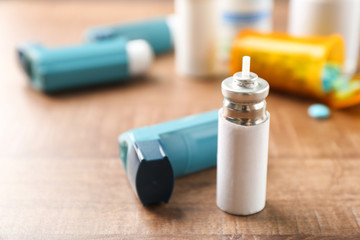 Asthma inhaler with cartridge on wooden table - obrazy, fototapety, plakaty