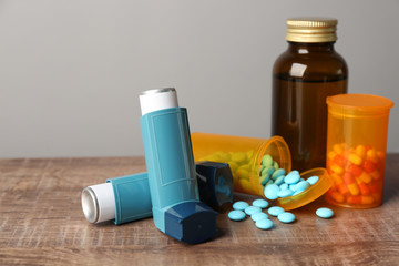 Asthma inhalers with medicines on wooden table