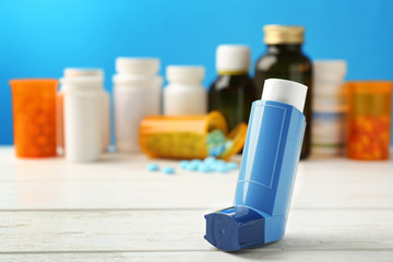 Asthma inhaler with medicines on blue background