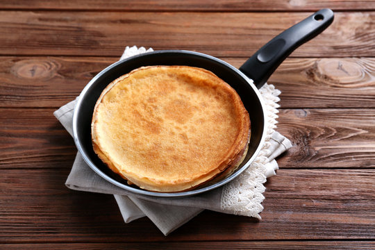 Tasty pancakes on pan on wooden table
