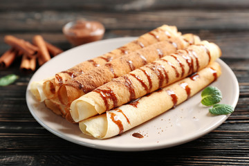Tasty rolled pancakes with chocolate on plate