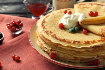 Tasty pancakes with cream and berries on table