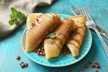 Tasty pancakes with chocolate syrup and nuts on plate